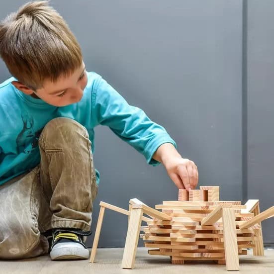 Bouwen met KAPLA 200 houten plankjes Kind bouwt met naturel houten plankjes uit de KAPLA 200 Box