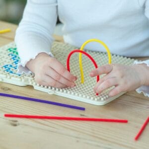 Kind speelt met TickiT SiliShapes activiteitendoolhof en gekleurde koorden