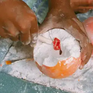 Kind graaft met houten gereedschap een rode steen uit een oranje KIDYPLANET planeet