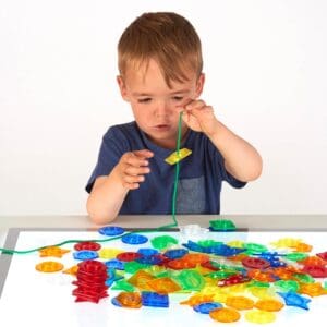 Kind sorteert Tickit stapelbare knopen op een lichtpaneel