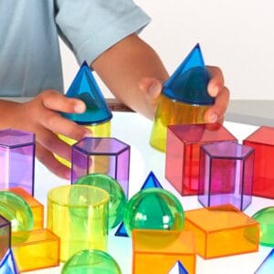 Doorschijnende vormen en telmaterialen uit de Tickit wiskundeset op een lichtpaneel