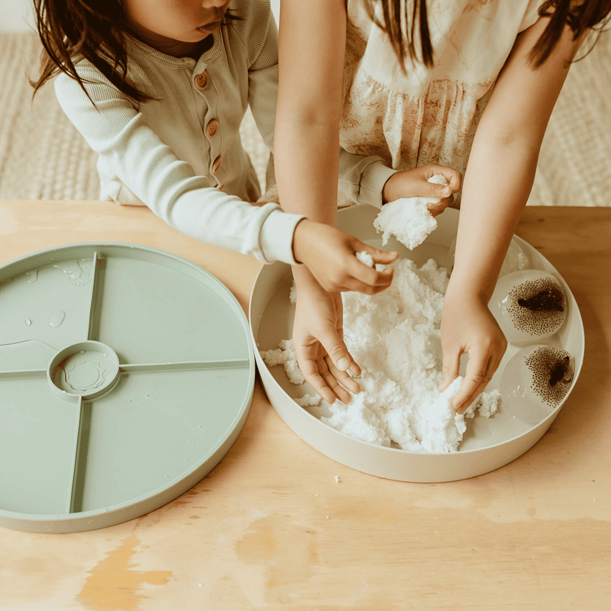 Jellystone Sensorische Sneeuw – samen ontdekken Twee kinderen voelen en kneden Jellystone sensorische sneeuw in een speelbak