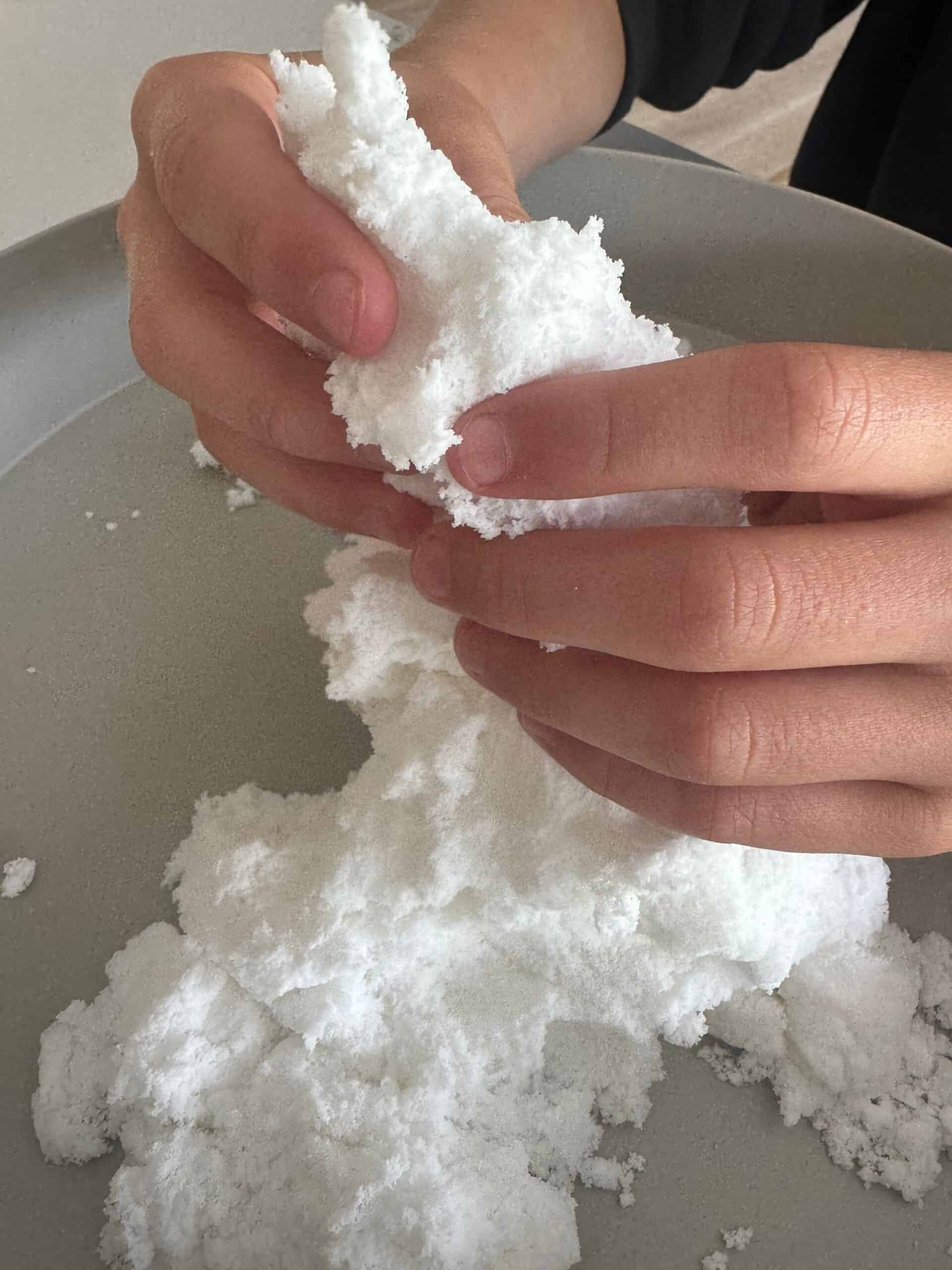 Jellystone Sensorische Sneeuw – structuur van dichtbij Close-up van handen die de zachte witte structuur van Jellystone Sensory Snow kneden