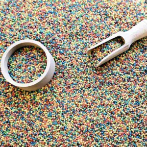 Speelvoorbeeld met SensoryFun regenboogparels, een houten schep en bakje