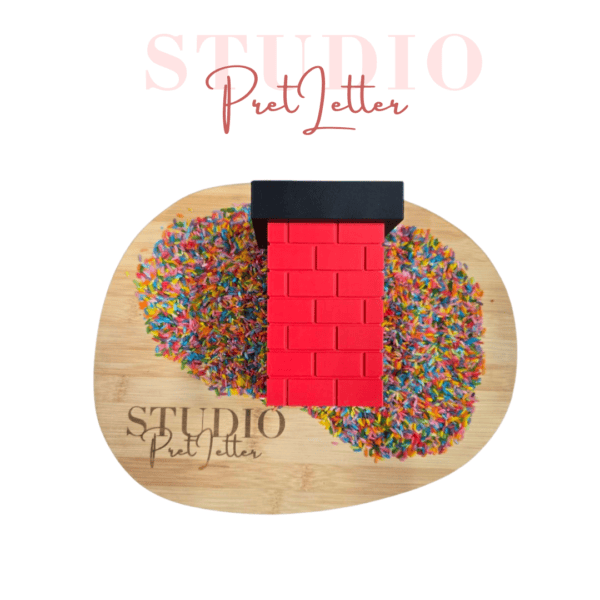 Rode Studio Pretletter speelschoorsteen met zwarte rand op een houten blad